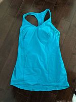 Front view of turquoise racerback athletic tank top laid flat