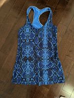 Front view of blue snake-print Lululemon racerback tank top on dark wood floor