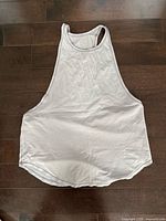 Front view of white Lululemon racerback tank top laid flat on floor