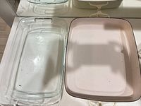 Clear glass baking dish beside pink rectangular enamel pan