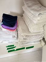 Stacked white towels, bath mats and colored makeup cloths inside cabinet