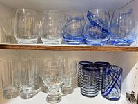Shelf showing assorted clear and blue glasses on two levels