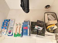 Full lot under sink showing oral care products lined up and fabric basket with boxed beauty items
