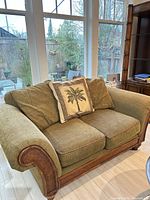 Front view of olive green loveseat with cushions and decorative pillow
