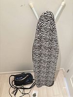 Ironing board with zebra cover, steam generator base, iron, hose, power cord, manual
