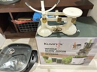 Kuvings juicer box, vintage balance scale and The Rock skillet grouped