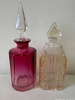 Front view of both perfume bottles side by side showing colour, shape and stoppers