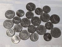 Top view of 24 French 1 Franc coins spread on cloth