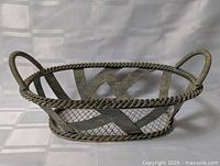 Side view of oval metal basket showing twisted rim and handles