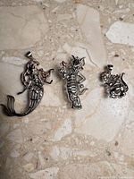 Front view of three sterling silver character pendants