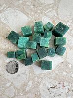 Top-down view showing majority of jade cubes beside a quarter for scale