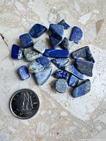 Group of lapis lazuli pieces beside Canadian dime
