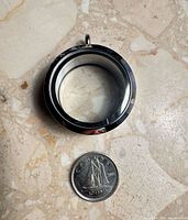 Open stainless steel locket beside Canadian dime for scale