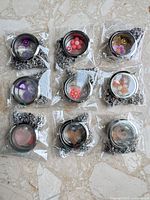 Nine individually bagged stainless steel lockets with chains displayed