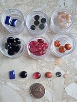 Overview of six pots with cabochons and coin for scale