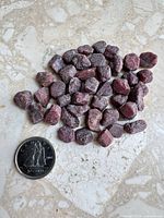 Pile of raw ruby stones with Canadian dime for scale