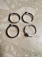 four sterling silver adjustable ring settings laid out on stone surface