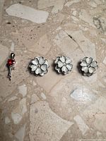 Three flower pendant settings and a rose pendant on stone surface