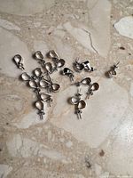 Group of 20 silver pendant bails on marble surface
