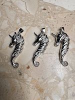 Three identical sterling silver unicorn pendant settings on stone surface