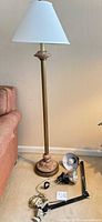 Full view of floor lamp with shade and clamp lamps on floor
