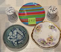 Group shot of both candle holders, striped plastic plate, Limoges floral plate, celadon bowl