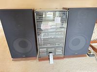 Full front view of stereo cabinet flanked by two speakers with remote shown