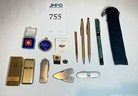 Full lot overview with pens, lighters, pins, medallion, knife and accessories