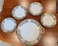 Five porcelain plates, one larger with handles, four smaller, showing full pattern