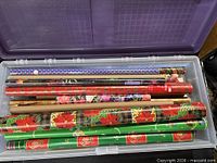 Open plastic bin showing multiple rolls of assorted wrapping paper