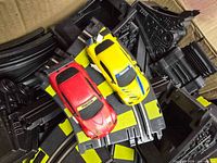Red and yellow Mazda slot cars on black/yellow track pieces