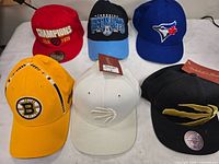All six sports team hats laid out in two rows
