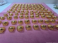 Rows of gold-plated Om signet rings laid out for quantity overview