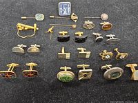 Entire collection of cufflinks and tie tacks displayed on black surface