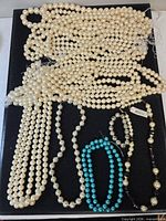 Overall view showing all faux pearl and bead necklaces on display board