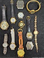 Overview of all twelve watches arranged on black surface