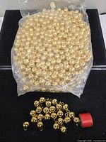 overall view of sealed bag of gold beads and loose beads