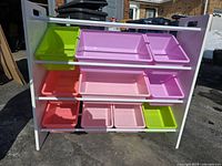 Front view of white frame toy organizer with nine multicolored plastic bins