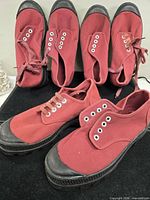 Front and top view of three pairs of burgundy canvas shoes showing uppers, laces, eyelets and toe caps