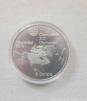 Reverse side showing Olympic rings, legends, North America map