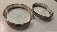 Two glass coasters showing silver rims and star-cut bases