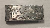 Front of sterling silver money clip showing engraved desert scene