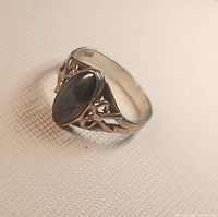 Full view of ring showing oval gemstone and filigree shoulders