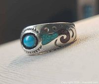 Oblique view of ring showing turquoise cabochon and inlay design