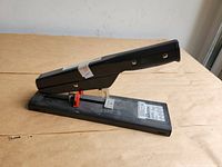 Side view of black Bostitch heavy duty stapler upright on base