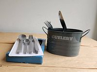 Cutlery sets in packaging alongside metal caddy