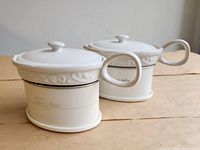 two white mini crock warmers side by side showing front logo and design