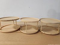 front view of three matching beige two-tier lazy Susans aligned side by side