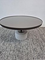 Full view of round glass-top coffee table on concrete base