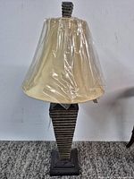 Full view of lamp showing base, shade wrapped in plastic